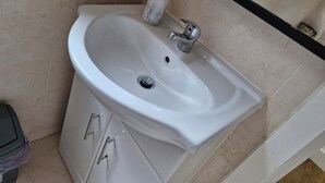 Une salle de bain avec un lavabo blanc, un distributeur de savon en marbre et une poubelle.