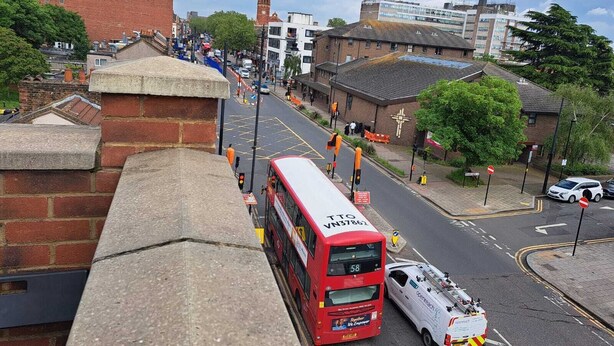 A red double-decker bus on a city street with buildings and a tower in the background. - Apartment Sleeps 4 with Free Parking (London)