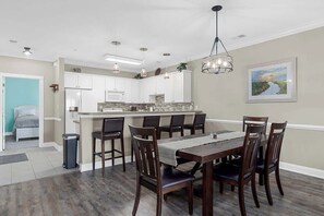 Una cocina moderna con armarios blancos, una isla central e iluminación colgante.