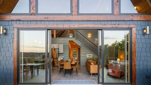 A modern house with a dining area, staircase, and large glass doors. - The Majestic Dragonfly Inn, overlooking Daniel Boone National Forest  (Frenchburg)