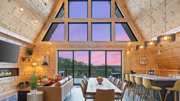 A spacious interior with a high ceiling, large windows, a fireplace, and a dining area. - The Majestic Dragonfly Inn, overlooking Daniel Boone National Forest  (Frenchburg)