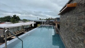 Una piscina en la azotea con un muro de piedra y una barandilla de metal.