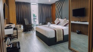 Habitación de hotel moderna con una cama grande, un escritorio, una silla, un televisor y vistas al exterior.