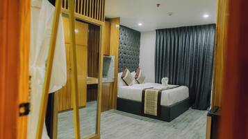 Una habitación de hotel moderna con una cama grande, un televisor y un armario de madera.