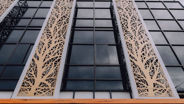 Fachada de edificio con amplias ventanas y paneles verticales decorativos.