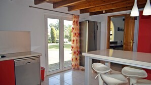 Cuina amb rentaplats, nevera i zona de menjador amb tamborets de bar.