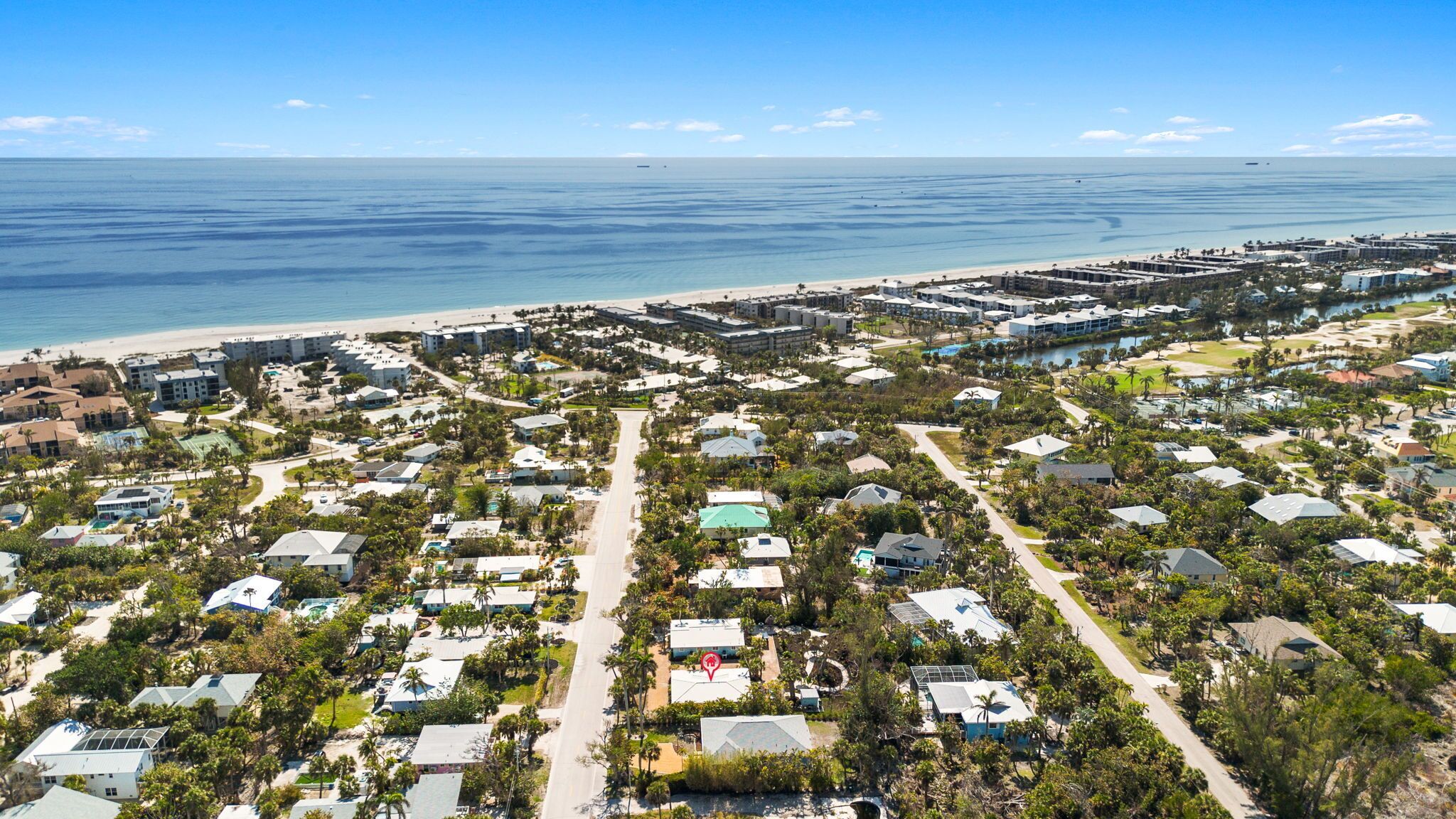 Vue aérienne d’une zone résidentielle côtière, avec des maisons, des routes et une plage.