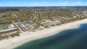 An aerial view of a coastal residential area with a beachfront, including a large hotel complex with multiple buildings and a parking lot. - Driftwood Inn (Sanibel)