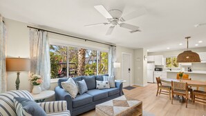 A modern living room with a sofa, a coffee table, and a dining area with a table and chairs. - Driftwood Inn (Sanibel)