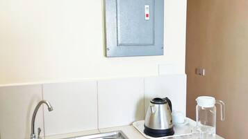 A kitchen with a stainless steel sink, a kettle, and a water pitcher on the counter.
