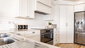 Una cocina moderna con armarios blancos, electrodomésticos de acero inoxidable y encimera de madera.