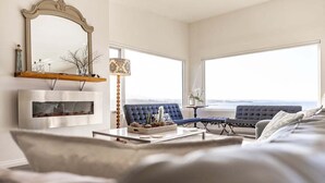 Una sala de estar moderna con un ventanal grande, un sofá azul, una mesa de centro y un espejo decorativo.