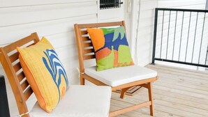 Two wooden chairs with cushions on a wooden deck.