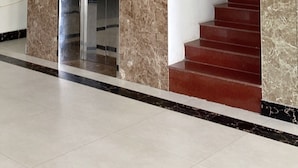 A modern elevator with a marble wall, a phone, and a red staircase. - Royal Hotel Cua Lo Beach (Cua Lo)