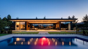 A modern house with a large glass facade, a swimming pool, and a well-maintained lawn. - Riverbank  - Hosted by NZSIR Luxury Rental Homes (Wānaka)