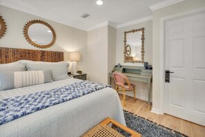 A bedroom with a bed, bedside table, lamp, chair, desk, mirror, and a door. - Less than a Mile to the Beach! Community Pool. (Saint Simons Island)
