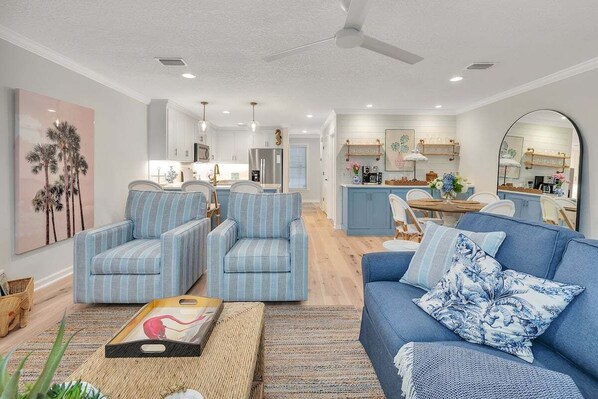 A modern living room with striped armchairs, a blue sofa, and a kitchen in the background. - Less than a Mile to the Beach! Community Pool. (Saint Simons Island)