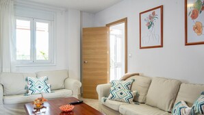 A living room with two beige sofas, a wooden coffee table, and a large window with curtains.
