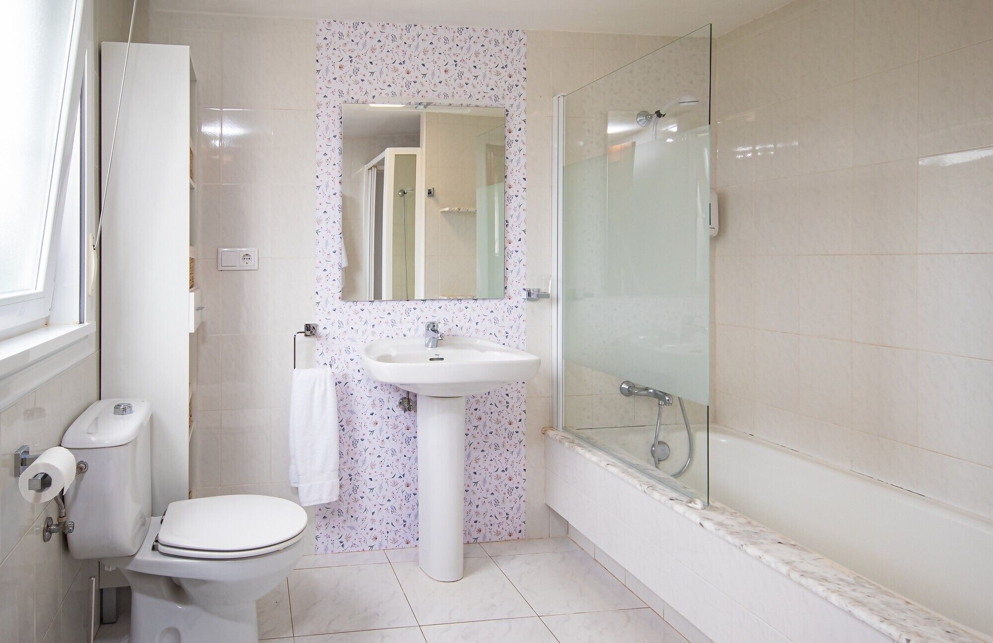 Un baño con inodoro, lavamanos y cabina de ducha de vidrio.