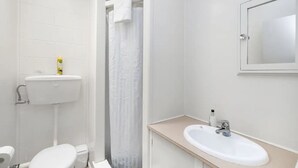 A modern bathroom with a toilet, sink, and shower area. - The Sands Motel (Tutukaka)