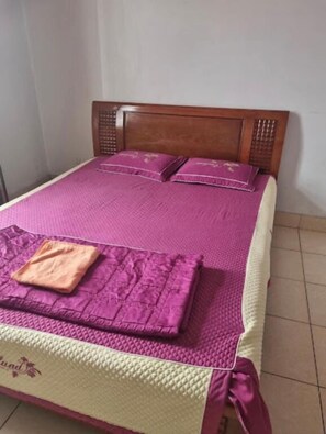 A bed with a wooden headboard, a pink quilt, and two pillows. - Khanh Linh Hotel Gia Lam - by Bay Luxury (Hanoi)