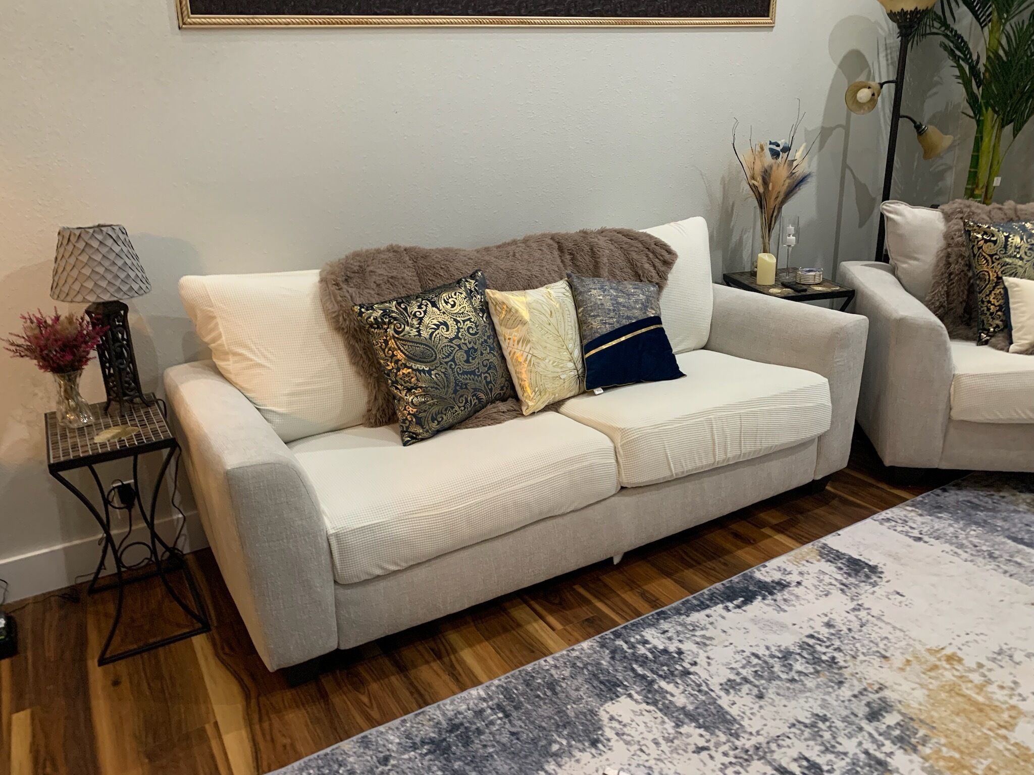 Una sala de estar con sofá, una mesita auxiliar, una lámpara y un jarrón decorativo.