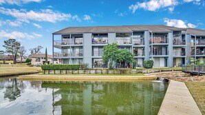 A multi-story residential building with balconies, a small pond, and a wooden deck. - Lake Conroe w/Theatre, Views, & Boat Launch Access & Walden's endless amenities  (Montgomery)