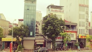 A street view with various buildings, including a modern glass building and a traditional building with a sign.