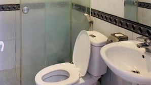 A bathroom with a glass-enclosed shower, a toilet, and a sink.