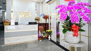 A reception area with a marble counter, a sign reading "Sunrise Airport", and a decorative shrine with flowers and statues. - Sunrise Airport Hotel (Ho Chi Minh City)