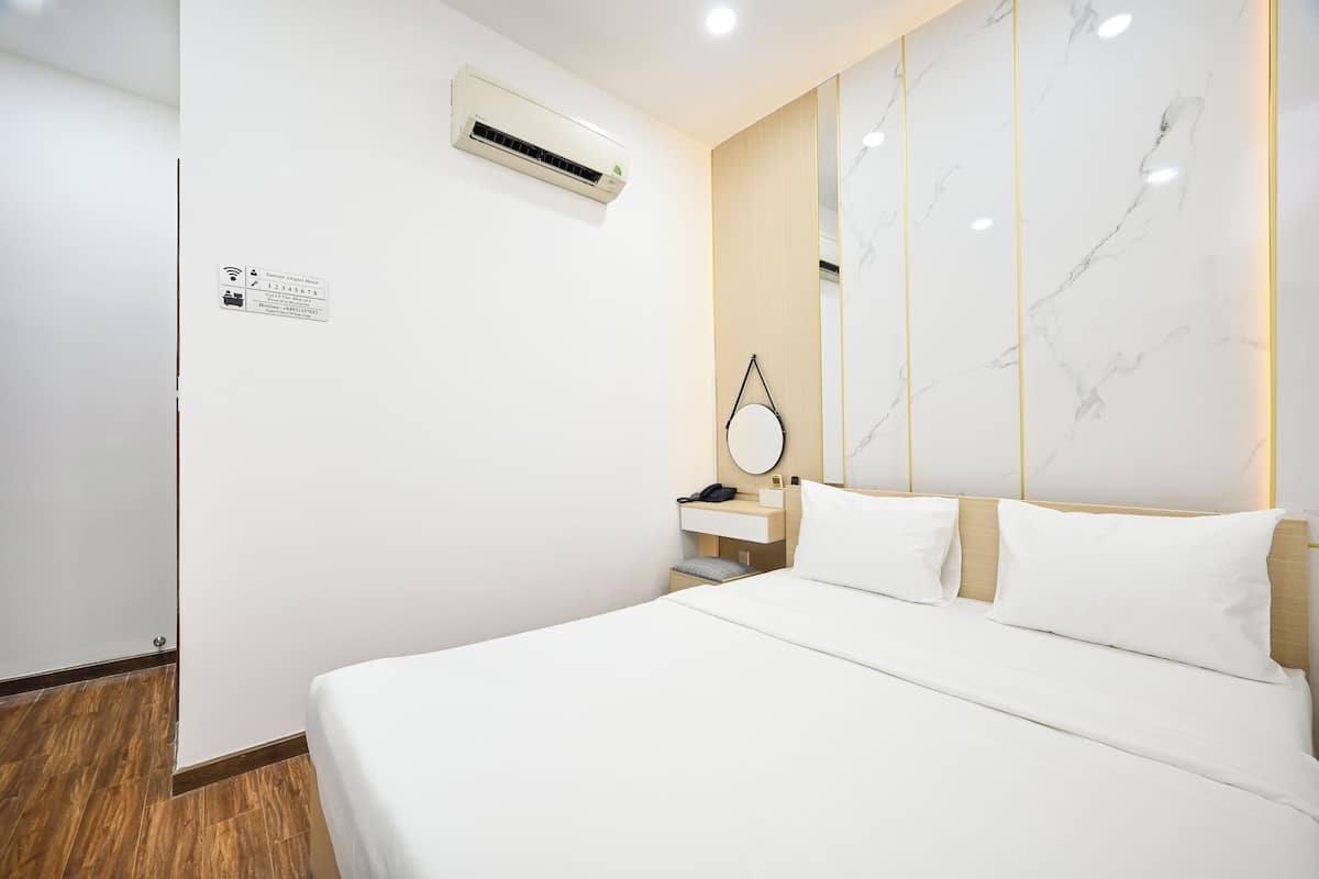 Une chambre d’hôtel comprenant un lit, une table de chevet avec une lampe, un appareil de climatisation et un mur en marbre.