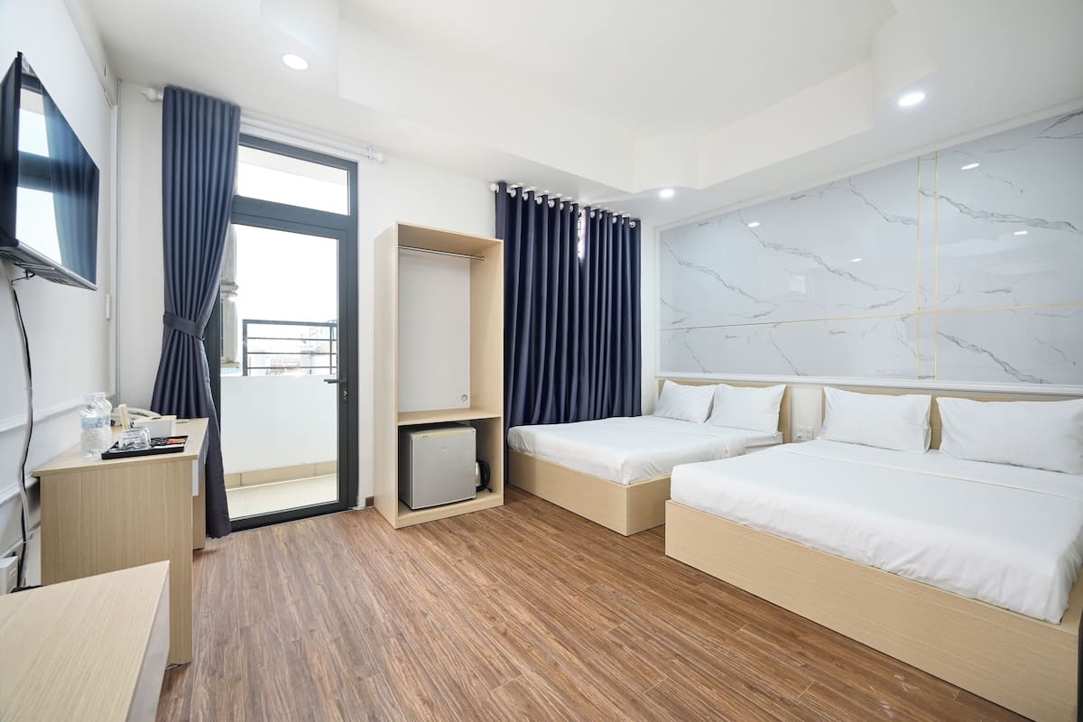 Une chambre d’hôtel moderne avec un plancher en bois, un lit, un bureau, une télévision et une armoire.