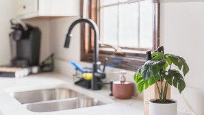 A kitchen with a sink, a coffee maker, and a potted plant. - Go Buckeyes!Stylish 3-Level Haven Near OSU,PS5,Skylight, Fully fenced Backyard (Columbus)