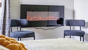 A modern room with a fireplace, two upholstered chairs, and a bed with a white blanket. - Go Buckeyes!Stylish 3-Level Haven Near OSU,PS5,Skylight, Fully fenced Backyard (Columbus)
