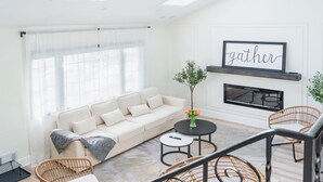 A living room with a sofa, two wicker chairs, a coffee table, and a fireplace. - Go Buckeyes!Stylish 3-Level Haven Near OSU,PS5,Skylight, Fully fenced Backyard (Columbus)