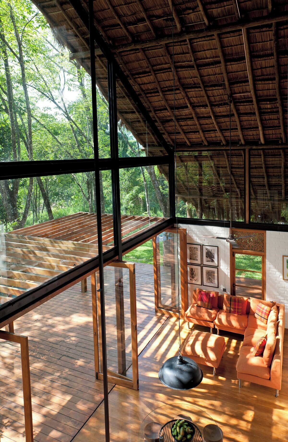 A modern interior with large windows, a wooden deck, and a sofa with cushions.