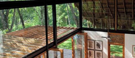 A modern interior with large windows, a wooden deck, and a sofa with cushions.
