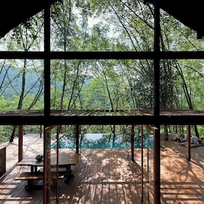 A wooden deck with a pool, surrounded by trees and a view of the landscape. - Guava House by The Serendipity Collection (Hemmathagama)