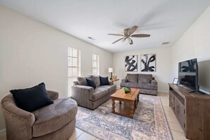 Ein Wohnzimmer mit zwei Sofas, einem Couchtisch, einem Fernseher und Kunstwerken an den Wänden.