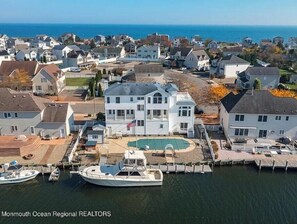 A coastal residential area with a large white house featuring a swimming pool and docked boats. - WATER FRONT VILLA Pool,Hot Tub,Elevator,85ft Dock near to  beach  28 days rental (Lacey Township)
