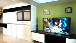 Ein modernes Wohnzimmer mit Flachbildfernseher, einer Couch und einem Essbereich mit Schränken.
