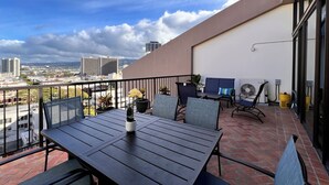 Ein Balkon mit Tisch und Stühlen, Blumentöpfen und Blick auf die Stadt.