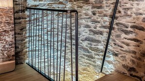 A wooden staircase leading to a stone-walled room with a metal gate.
