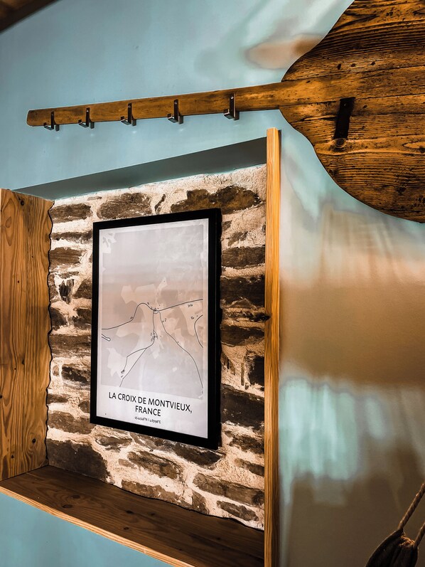 A framed map of Montville, France, mounted on a stone wall with a wooden shelf above.