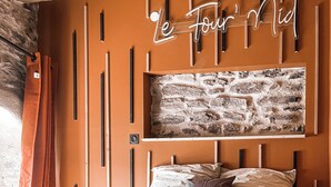 A bedroom with a bed, a wall-mounted artwork, and a wooden headboard.