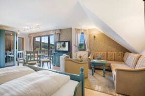 A bedroom with two beds, a sofa, a TV, and a dining area with chairs and a table. - 'Superior Einraumappartement mit Infrarotkabine' (Marienberg)