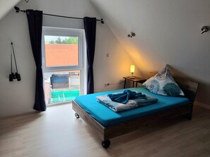 Un dormitorio con cama, lámpara y ventana.