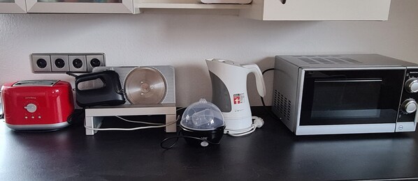 Une cuisine équipée d’un grille-pain, d’une bouilloire, d’un four à micro-ondes et d’un petit appareil électroménager posé sur un plan de travail.