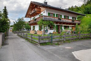A traditional two-story building with a balcony, a wooden fence, and a paved pathway.
