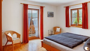 A bedroom with a bed, a chair, a small table, and a window with curtains. - Apartment 'Ferienwohnung Regina' with Mountain View, Balcony and Wi-Fi (Mittenwald)